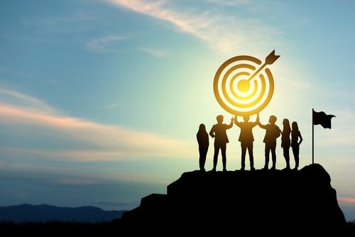 Bullseye held up by group of people in shadow at sunrise